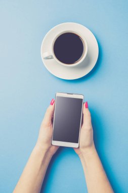 Telefon tutarak ve kahve içme kadın. Üstten görünüm