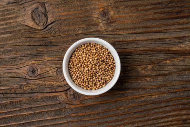 Eski bir ahşap masa üzerinde beyaz kase kuru kişniş