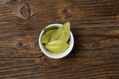 Defne yaprakları eski bir ahşap masa üzerinde beyaz kase