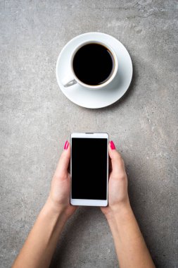 Akıllı telefon gri taş masa üzerinde tutan kadın