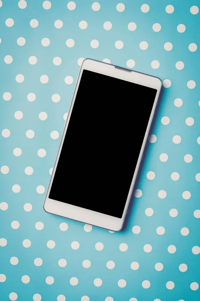 青い点線の背景に白の携帯電話 — ストック写真