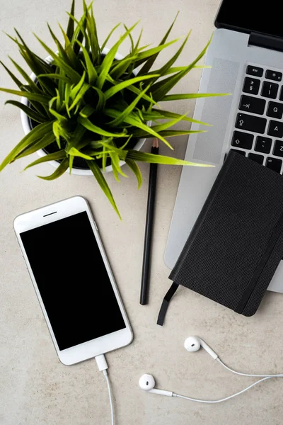 Modern laptop with smart phone and accessories on gray stone table