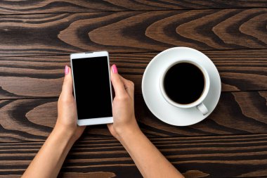 Ahşap masa üzerinde bir akıllı telefon kullanan kadın. Yakın çekim