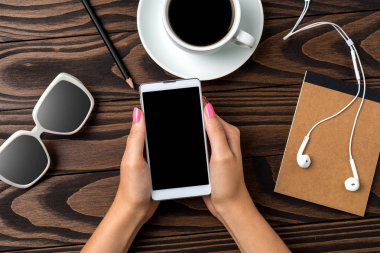 Ahşap masa üzerinde bir akıllı telefon kullanan kadın. Yakın çekim