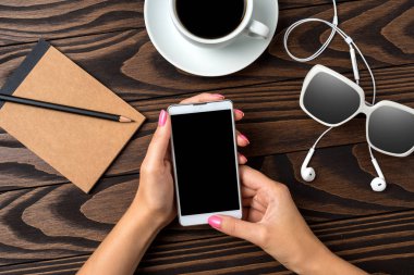 Ahşap masa üzerinde bir akıllı telefon kullanan kadın. Yakın çekim