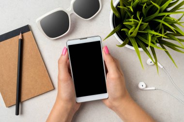 Gri taş masa üzerinde bir akıllı telefon kullanan kadın. Yakın çekim