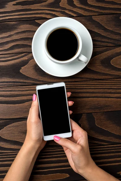 Ahşap masa üzerinde bir akıllı telefon kullanan kadın. Yakın çekim