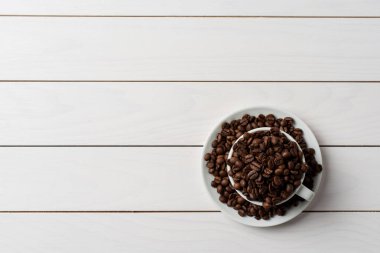 İçinde beyaz kahve fincanı kavrulmuş kahve çekirdekleri