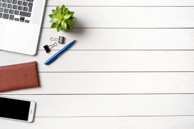 Beyaz ahşap ofis masaüstü laptop ve iş malzemeleri ile. Üstten görünüm