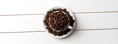 İçinde beyaz kahve fincanı kavrulmuş kahve çekirdekleri. Üstten görünüm