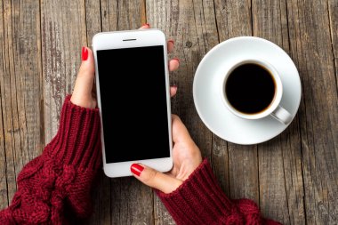 Sıcak süveterin içinde bir akıllı telefon kullanan kadın. Yakın çekim