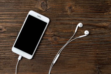 Eski bir ahşap zemin üzerinde kulaklık ile modern smartphone