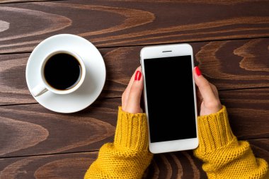 Ahşap arka plan üzerinde bir akıllı telefon kullanan kadın