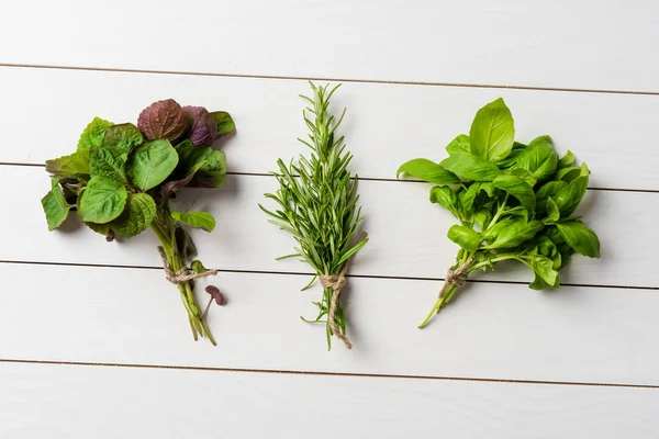 Bunches of fresh herbs on white wooden table