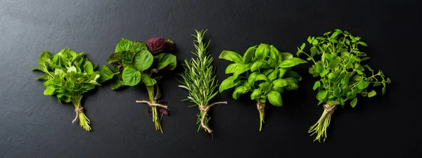 Bunch of fresh herbs on black concrete background. Close up
