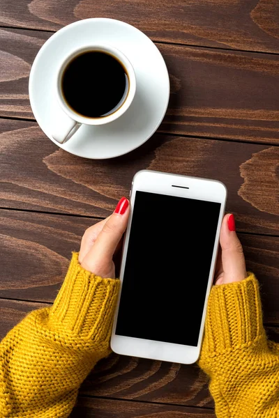 Ahşap arka plan üzerinde bir akıllı telefon kullanan kadın