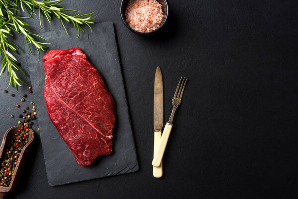 Raw beef steak on dark concrete table. Food background