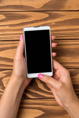 Akıllı telefon ahşap masa üzerinde tutan kadın. Yakın çekim