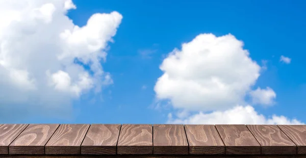 Empty wooden table against blurred sky background