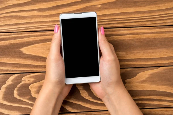 Mujer Sosteniendo Teléfono Inteligente Sobre Mesa Madera Cerca — Foto de Stock