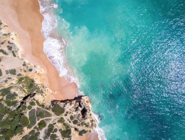 Tropikal kumlu plaj, uçurumlar ve okyanus havadan görünümü.