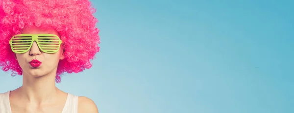 Portrait of beautiful woman in pink wig and green glasses with copy space