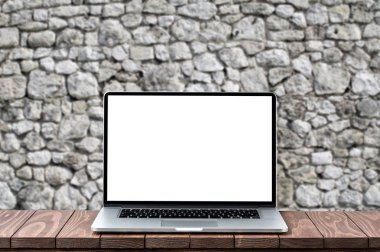 Bulanık eski tuğla duvara ahşap masa boş beyaz ekran ile modern dizüstü bilgisayar