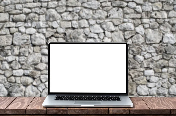 Bulanık eski tuğla duvara ahşap masa boş beyaz ekran ile modern dizüstü bilgisayar