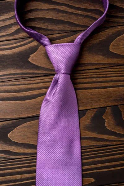 Purple necktie on an old wooden table. Close up