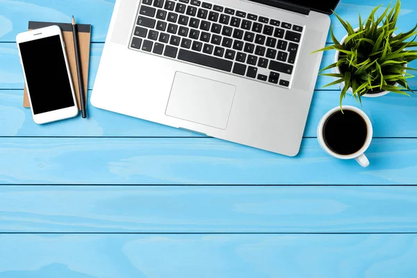 Office masaüstü mavi ahşap arka plan üzerinde modern dizüstü bilgisayar ile. Üstten görünüm