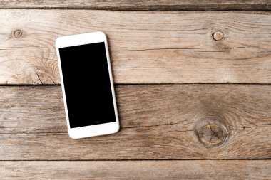 Ahşap masasında boş ekranı olan akıllı bir telefon. Üst görünüm 