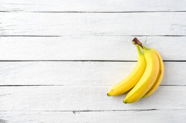 Beyaz ahşap arka planda muzlar. Meyve arkaplanı