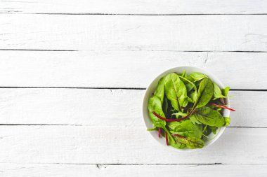Ispanaklı yeşil salata, roka ve pancar yaprakları beyaz ahşap masada, kopyalanmış. Üst görünüm