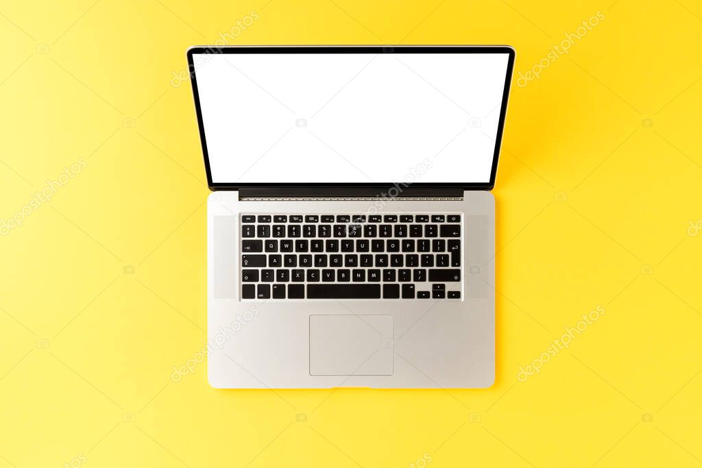 Laptop with empty screen on yellow background. Office desktop concept. Top view
