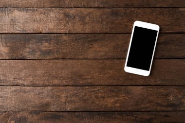 Ahşap masaüstünde boş ekranlı cep telefonu. Üst görünüm