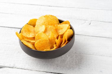 Beyaz tahta masada patates cipsi kasede. Kapat.