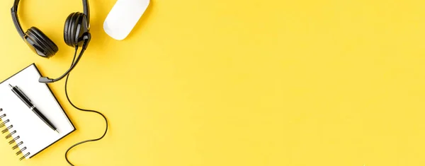 黄色のテーブルの上にヘッドセットやアクセサリーとコールセンターのデスクトップ パノラマのバナー トップ表示 — ストック写真