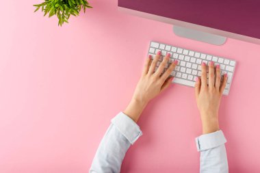Pembe arka planda modern bilgisayar kullanan kadın eller. Ofis masaüstü. Üst görünüm