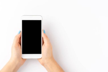 Beyaz arka planda izole edilmiş boş ekranlı cep telefonu kullanan kadın elleri. Üst görünüm