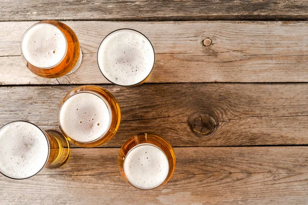 Overhead shot of beer glasses on wooden table.