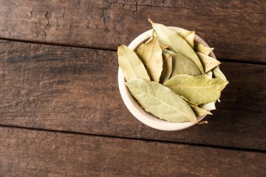 Kurumuş defne yaprakları ahşap masada kasede. Kapatın. Üst görünüm