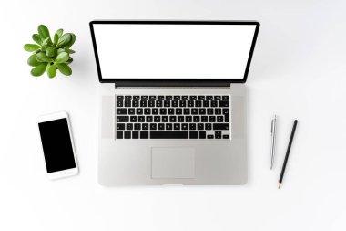 Boş ekran ve beyaz arka planda iş aksesuarları olan bir dizüstü bilgisayar görüntüsü. Ofis masaüstü. Düz yatıyordu
