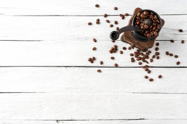 Beyaz ahşap masa üzerinde kuru fasulyeli klasik kahve öğütücüsü. Üst görünüm