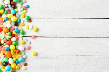 Beyaz ahşap masada çeşitli renkli tatlılar. Üst görünüm