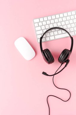 Pembe masaüstünde bilgisayar aksesuarları olan müşteri hizmetleri kulaklığı. Çağrı merkezi kavramı