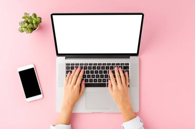 Dizüstü bilgisayarda boş ekranla çalışan kadın eller. Aksesuarlı ofis masası. Üst görünüm