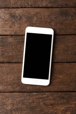 Ahşap masasında boş ekranı olan akıllı bir telefon. Üst görünüm 