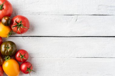 Beyaz ahşap arka planda farklı domatesler. Üst görünüm