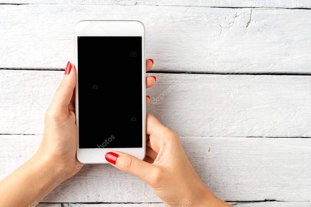 Female hands holding mobile phone with copyspace. Top view