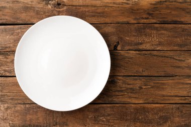 Kırsal ahşap masada boş beyaz tabak. Üst görünüm